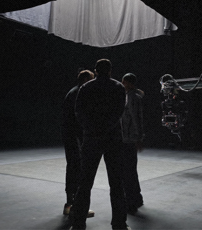 Crew gathered under a softbox on a dark stage.